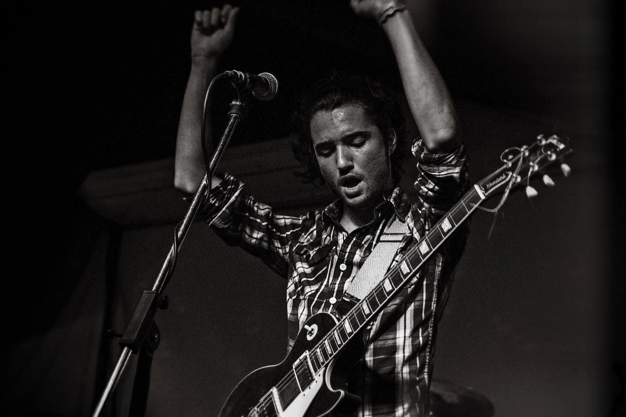 Grynn on stage with arms raised, black and white